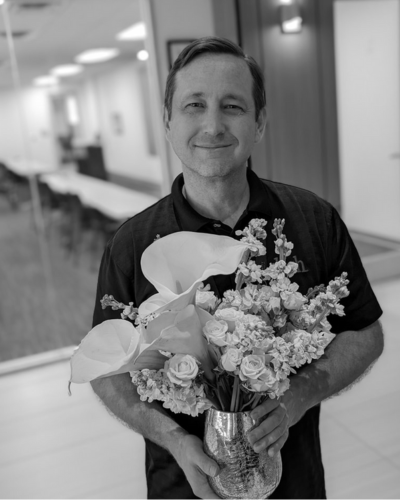 Man smiling and holding a bouquet of flowers