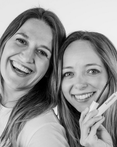 Smiling women holding a mascara tube